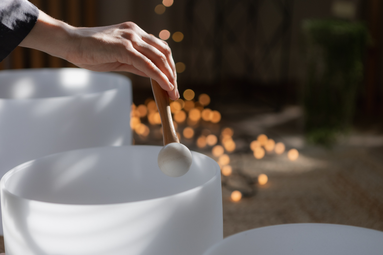 Hand playing crystal singing bowl during sound therapy session at home