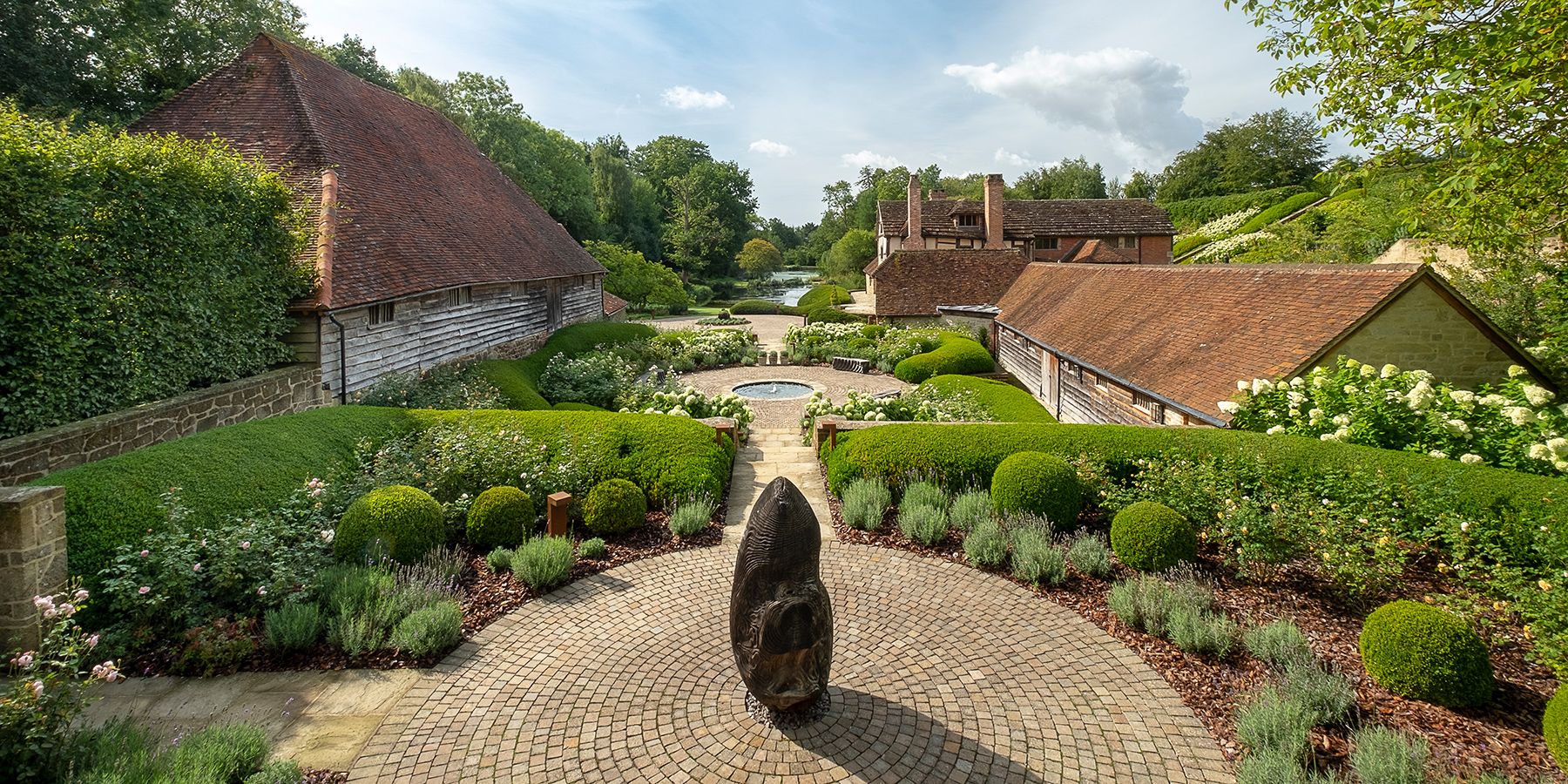 Beautifully manicured garden with water features surrounded by historic timber-framed houses